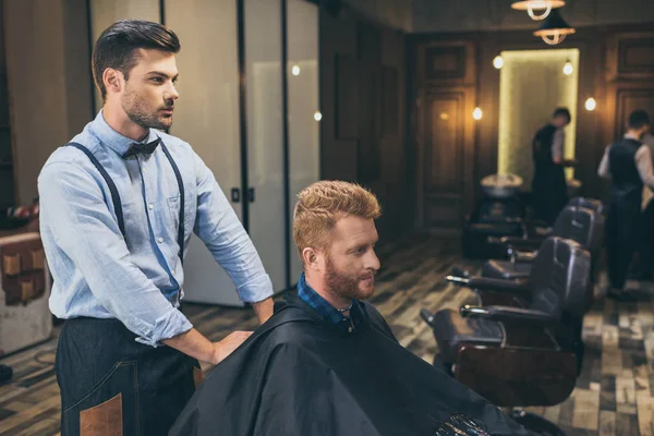 Barbeiro com cliente na barbearia — Fotografia de Stock