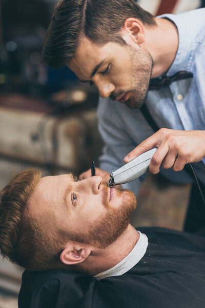 barber trimming customers beard