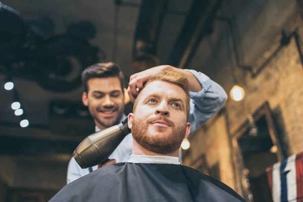 Barbiere asciugando capelli di cliente — Foto Stock