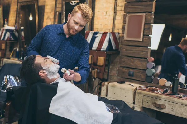 Barbeiro aplicando espuma antes de fazer a barba — Fotografia de Stock