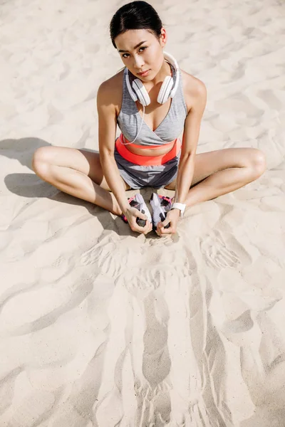 Спортсменка, растянувшаяся на песке — стоковое фото