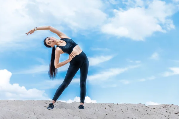 Sportswoman stretching against sky — Free Stock Photo