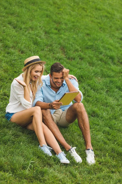 Пара з планшетом на зеленому газоні — стокове фото