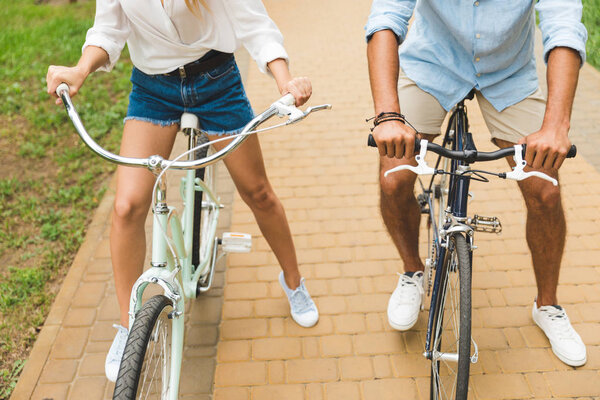 couple with hands on bicycle handle bars
