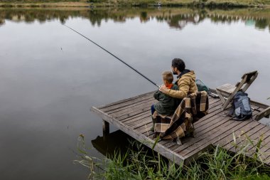 Baba ve oğul iskelede balık tutuyor.