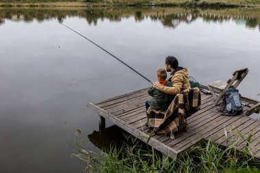 father and son fishing on pier clipart