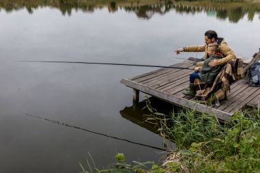 father and son fishing with rods clipart