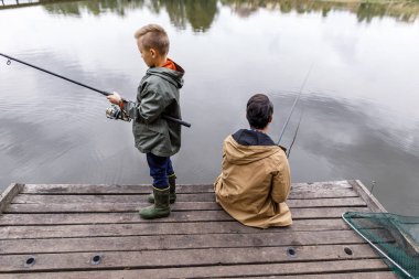 father and son fishing with rods clipart