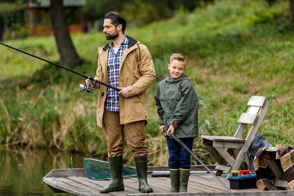 Отец и сын рыбачат на пирсе