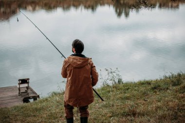 man fishing with rod on lake clipart