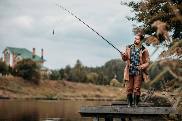 man fishing with rod at lake