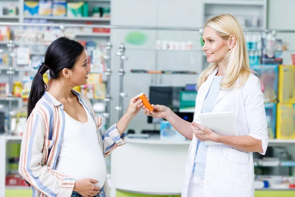 Фармацевт дает таблетки беременной женщине — стоковое фото