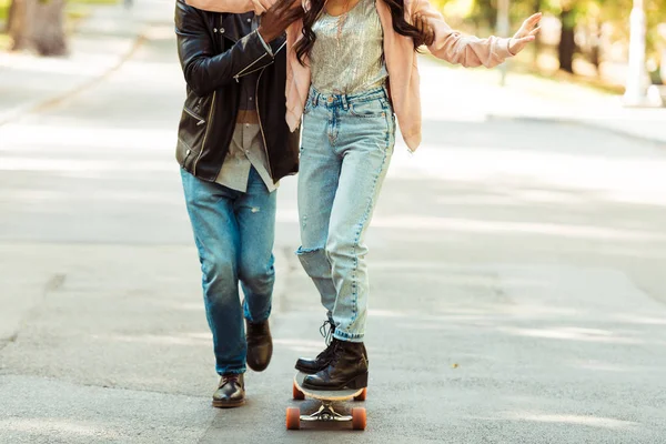 Freund hilft Freundin beim Skaten auf Longboard — kostenloses Stockfoto