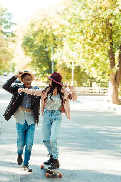 Vriendje helpen vriendin schaatsen op longboard — Stockfoto