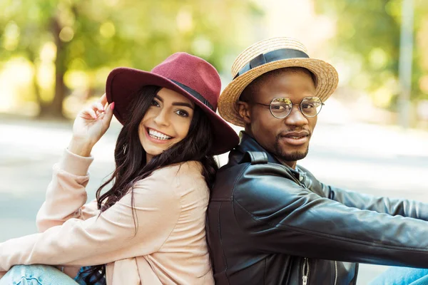 Couple in hats sitting back to back — Stock Photo, Image