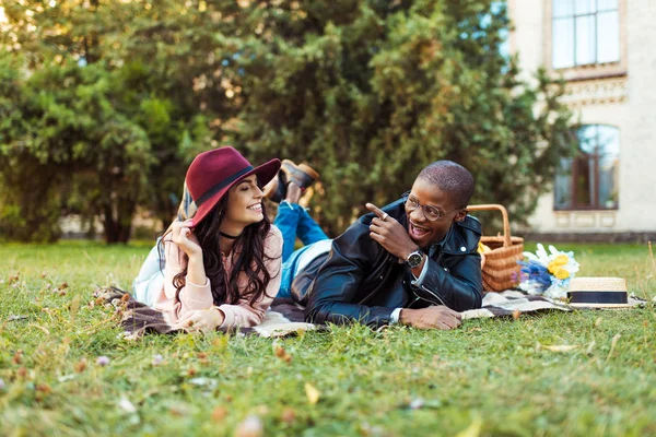 Multicultural couple lying on blanket in park — Stock Photo, Image