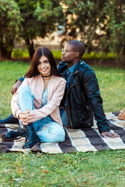 Multicultural couple sitting on blanket — Free Stock Photo