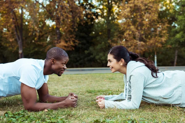 Casal exercitando prancha na grama — Fotografia de Stock