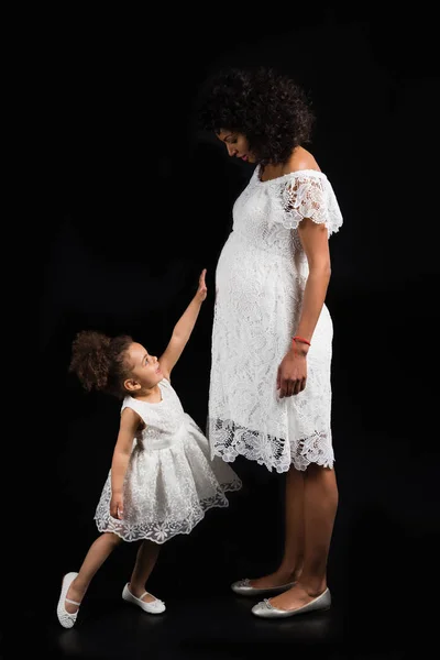Дочь трогает беременных матерей живот — стоковое фото