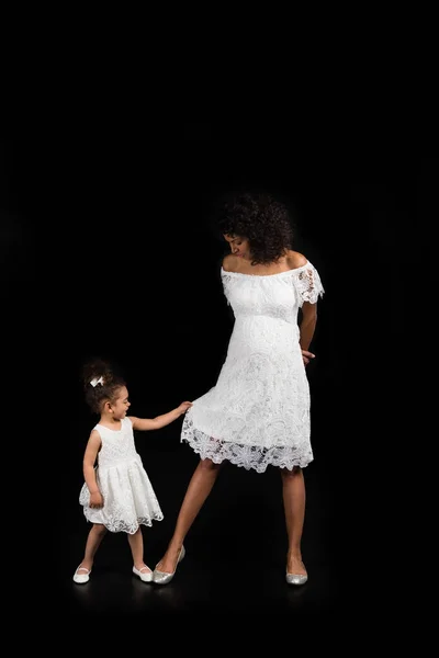 Small daughter playing with mothers dress — Free Stock Photo