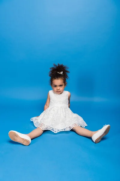 Serious child sitting on floor in dress — Stock Photo, Image