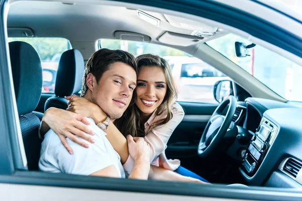 Pareja feliz sentada en el salón de coches — Foto de Stock