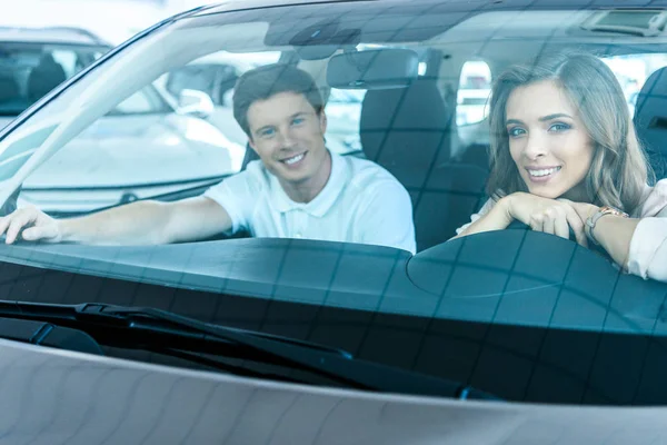 Pareja sentada en coche en sala de exposición —  Fotos de Stock