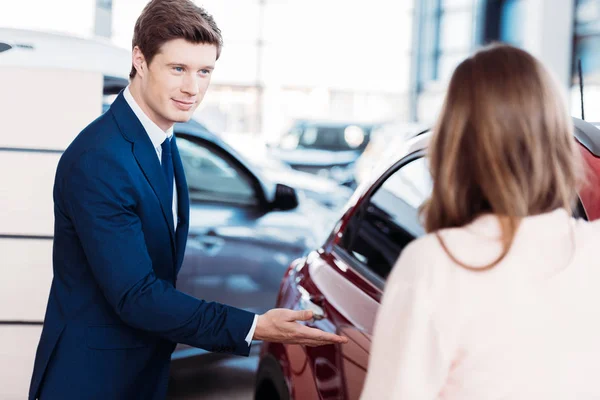 Manager inviting customer sit into car — Stock Photo, Image