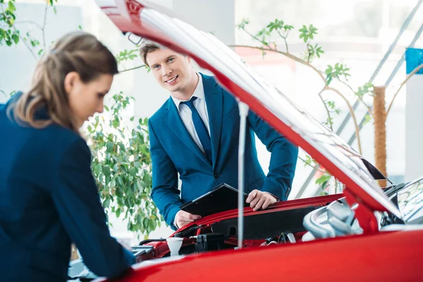 Managers looking under car hood — Stock Photo, Image