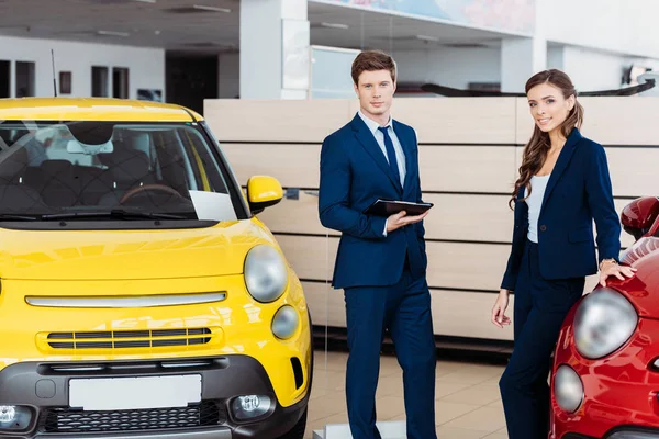 Directeurs des ventes posant dans la salle d'exposition de voiture — Photo