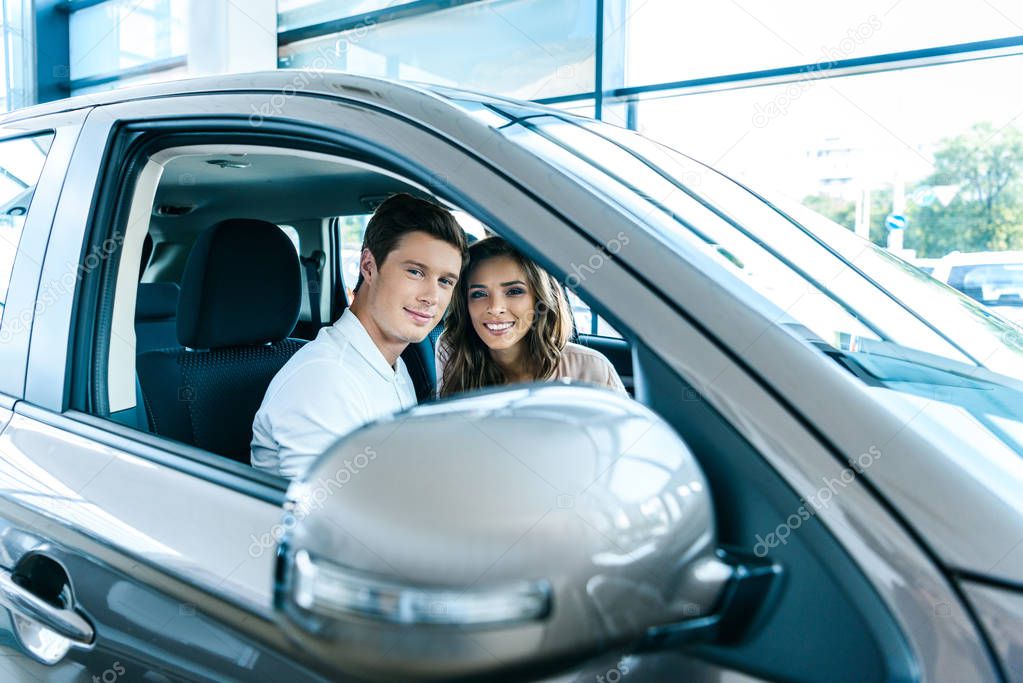 couple sitting in car in showroom 