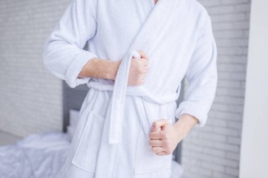 mid section of man wearing bathrobe at home clipart