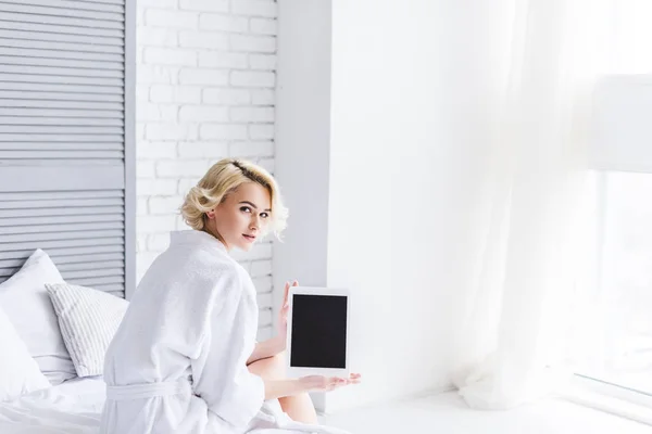 Hermosa Joven Sentada Cama Sosteniendo Tableta Digital Con Pantalla Blanco —  Fotos de Stock