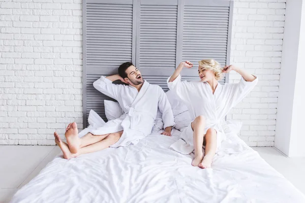 在床上舒展的快乐的年轻夫妇的全长视图 — 图库照片