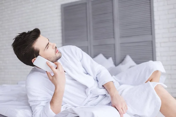 Barbuto Giovane Uomo Parlando Smartphone Guardando Lontano Mentre Sdraiato Sul — Foto stock gratuita