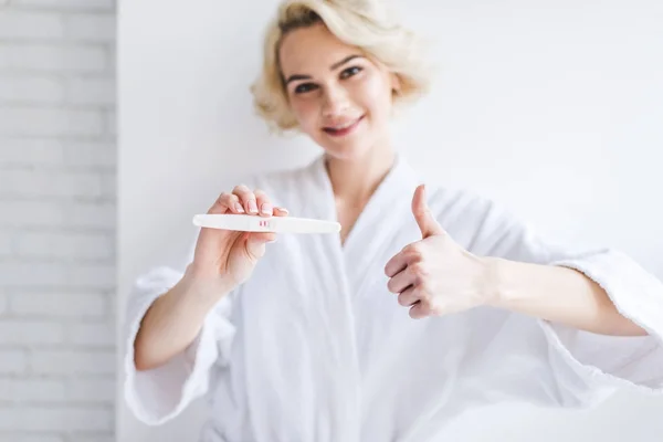 Улыбающаяся Молодая Женщина Держит Положительный Тест Беременность Показывает Большой Палец — стоковое фото
