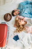 overhead view of couple of tourists lying on bed in hotel room