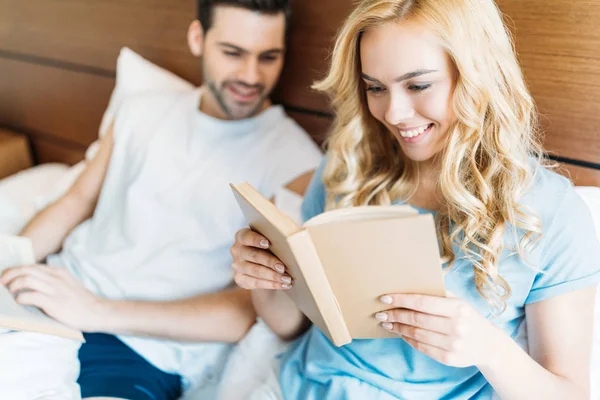 smiling couple reading books in bed