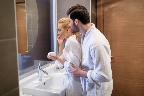 Affectionate Couple Looking Mirror White Bathrobes Bathroom — Stock Photo, Image