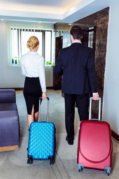 ビジネスマンやビジネスウーマン ホテル エレベーターが荷物を持って歩くの背面図 — ストック写真