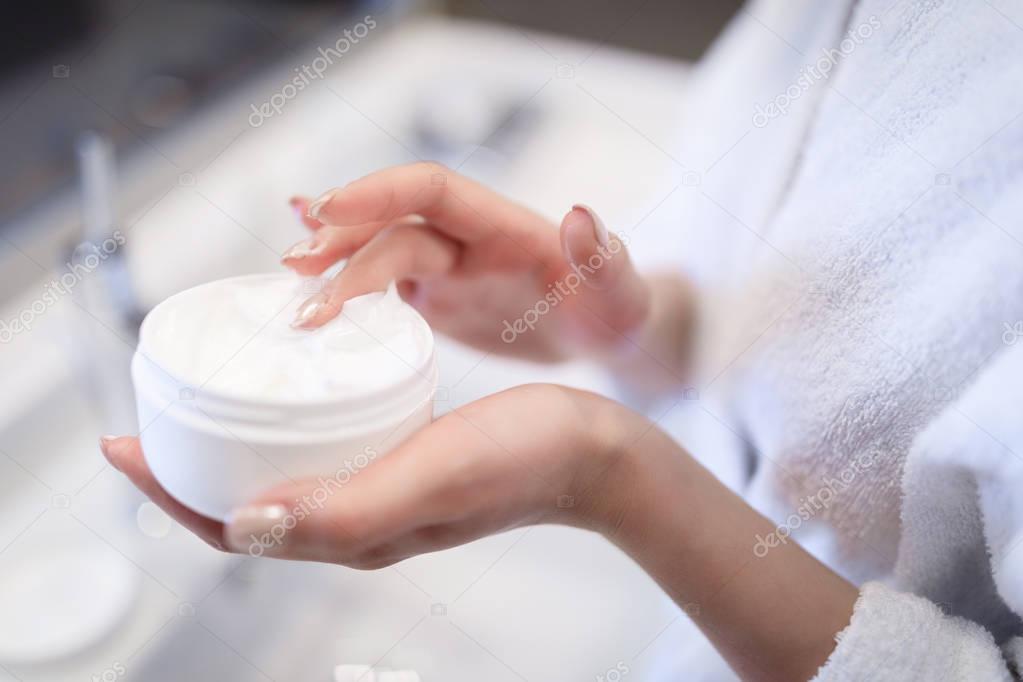 cropped image of girl taking cream in bathroom 
