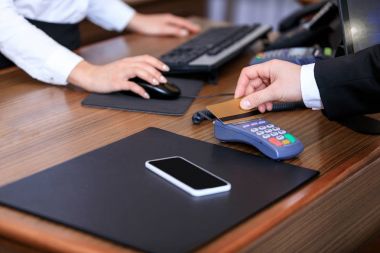 cropped image of businessman paying with credit card at reception desk in hotel clipart