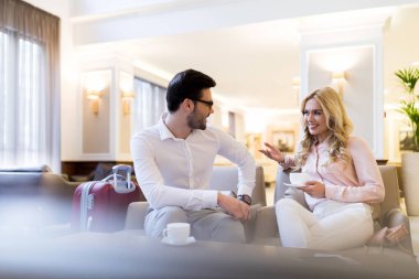 otel salonunda konuşurken yolcuları gülümseyen Çift