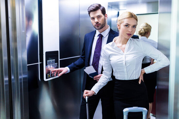 бизнесмен и деловая женщина в лифте отеля смотрят в камеру
