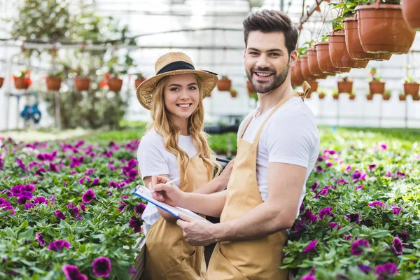 Jóvenes Jardineros Sosteniendo Portapapeles Por Flores Invernadero — Foto de Stock