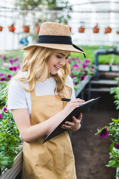 Mujer Sonriente Dueña Invernadero Con Portapapeles Llenado Flores — Foto de Stock