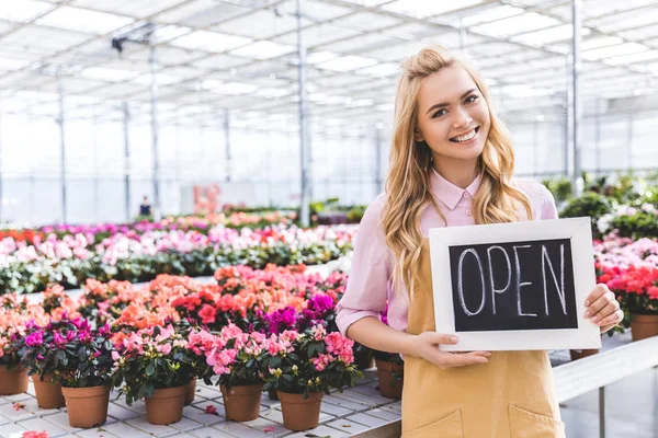 Blonde Woman Holding Open Board Flowers Greenhouse — Stock Photo, Image