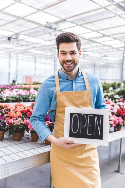 Young Man Holding Open Board Flowers Greenhouse — Stock Photo, Image