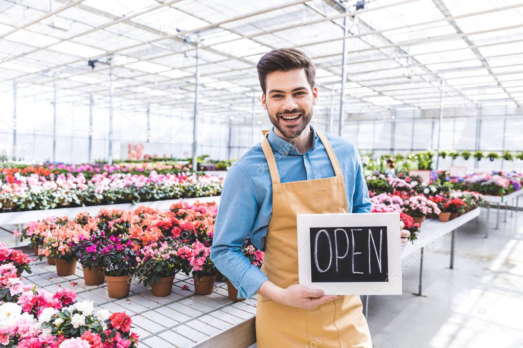 Male owner of greenhouse with Open board by flowers