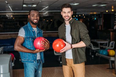 Kameraya bakarak bowling Club topları ile mutlu genç erkekler